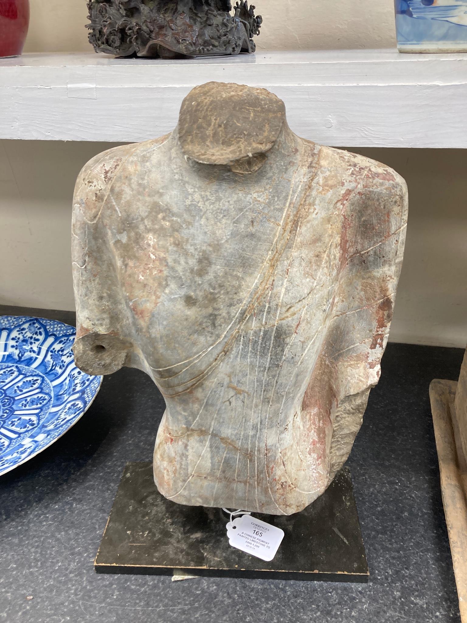 A Chinese pigment painted limestone torso of Buddha, probably Northern Qi dynasty (550-577 CE), 36cm high, mounted on a later base, total height 42.5cm